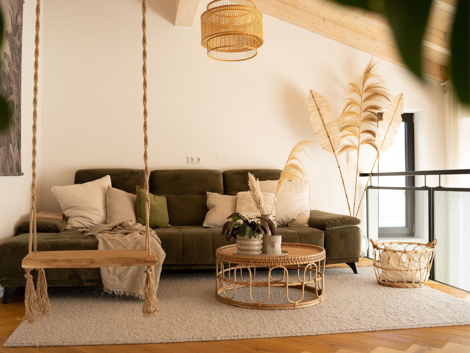 Handwebteppich Karlstad im modernen Wohnzimmer mit grünem Sofa, Hängeschaukel und Naturdeko in warmem Boho-Stil