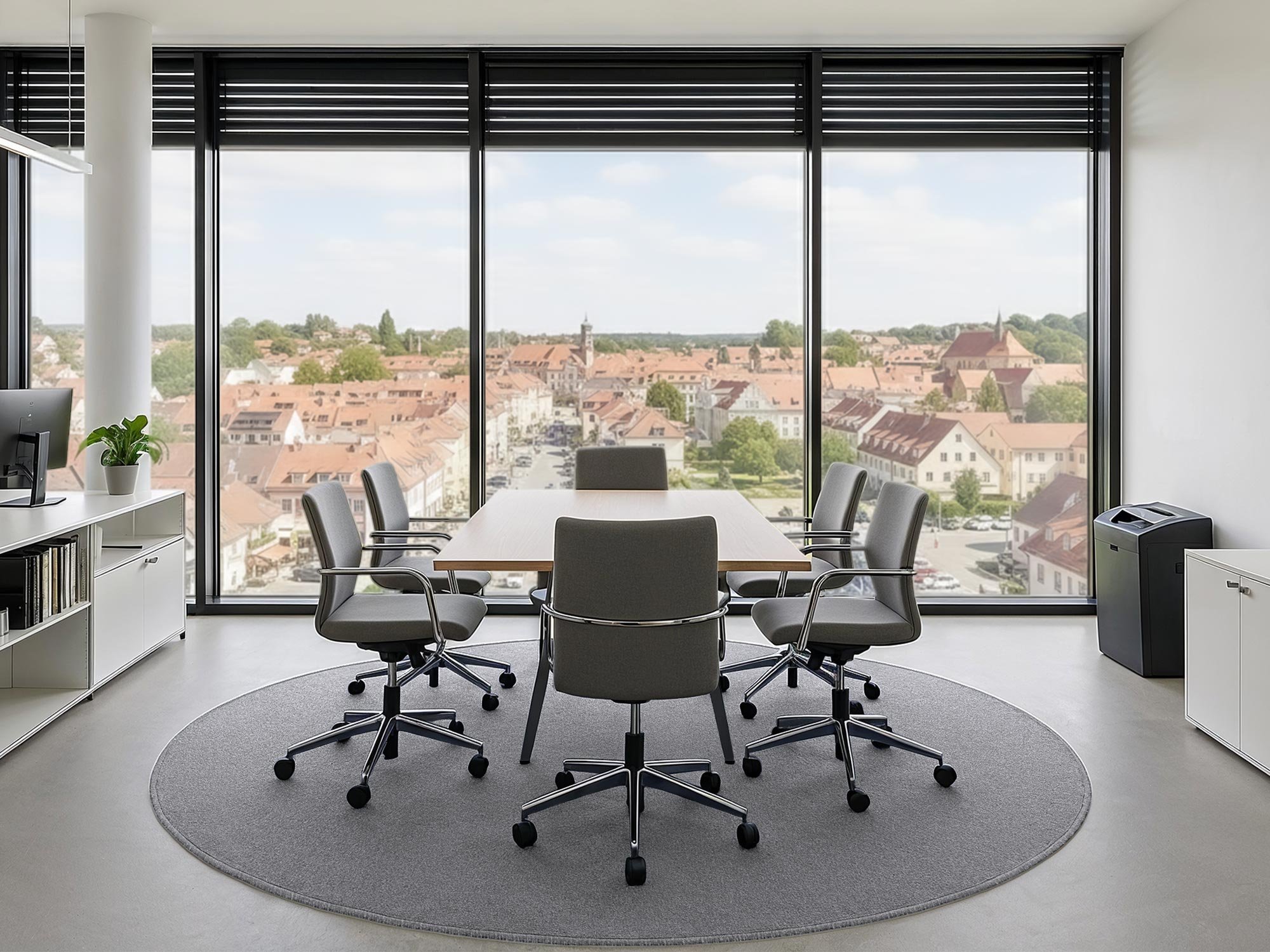 Der runde Kurzflorteppich Anteo in Grau liegt in einem Büro unter einem Konferenztisch mit Bürostühlen