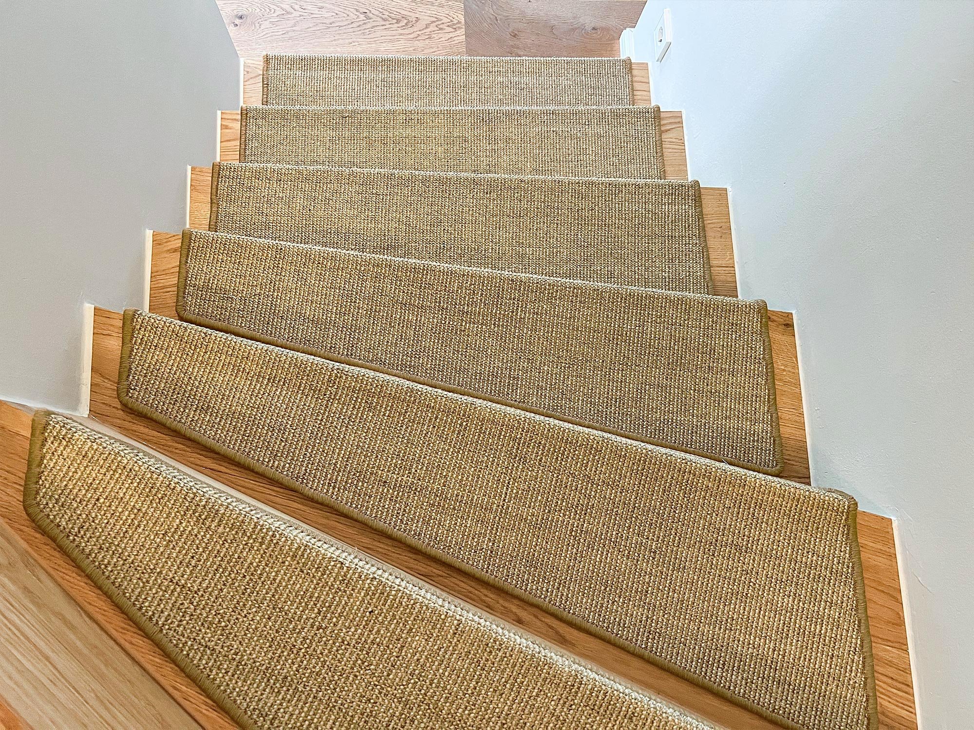 Eine Wendeltreppe mit Murcia Stufenmatten aus Sisal in hellen Beigtönen